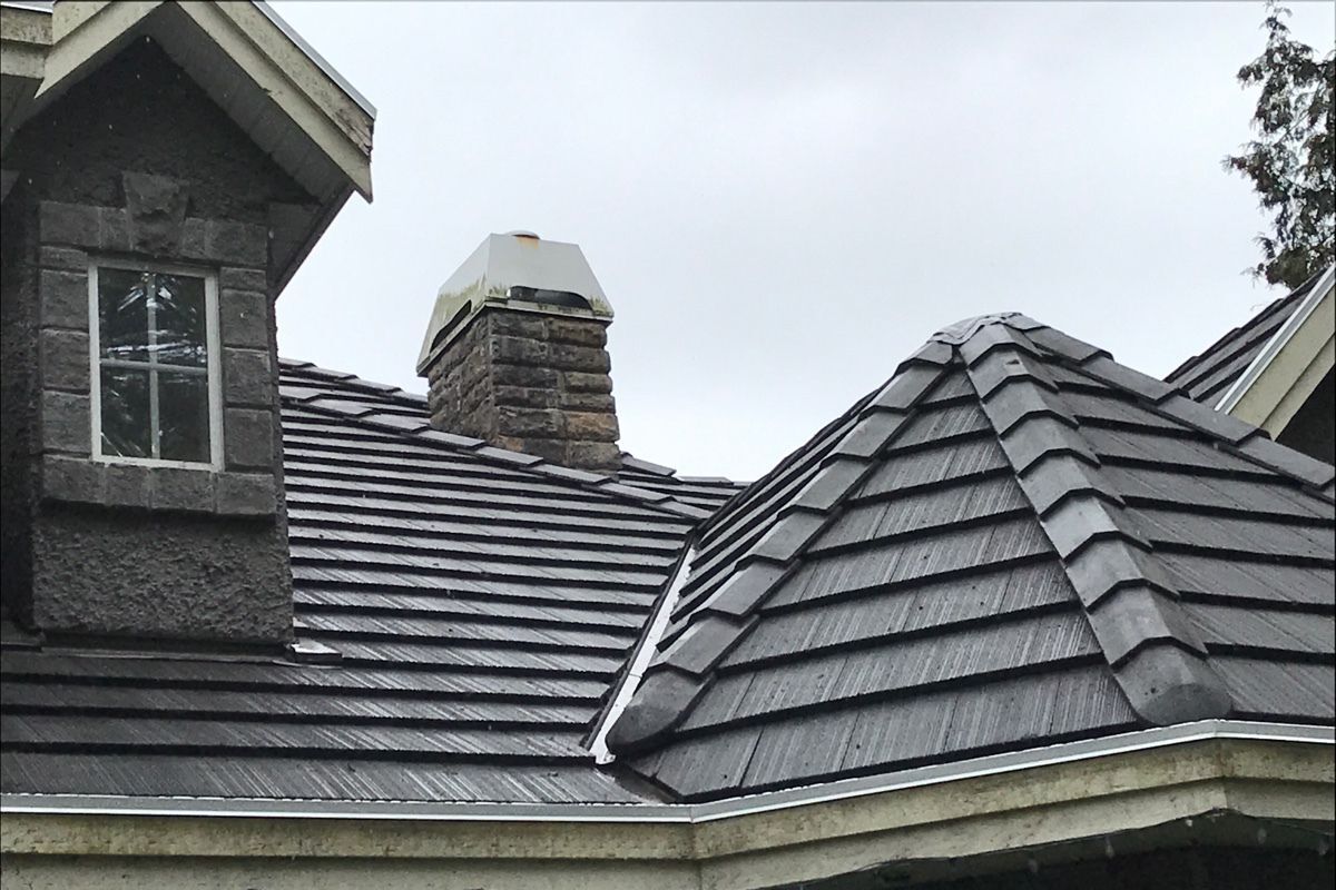 Black metal tile roof installation on a home in Vancouver with chimney, dormer window and valley flashing