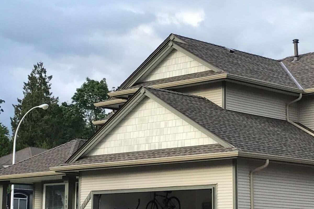 New asphalt shingles installed on a Vancouver home with light siding, gutters and clean rooflines