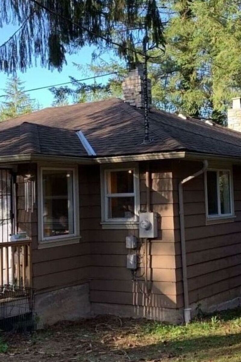 Brown asphalt shingle roof replacement on a small home in Vancouver with chimney and trees