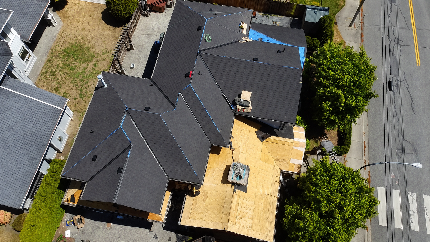 Aerial view of a North Vancouver roof replacement project with asphalt shingles, exposed roof decking, and roofing materials on site.