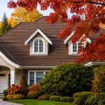 Autumn view of a North Vancouver home with a cedar shingle roof, dormer windows, red maple foliage, and mature landscaping.