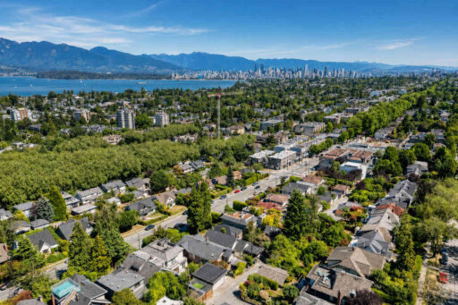 Aerial view of North Vancouver neighbourhoods with downtown Vancouver skyline, Burrard Inlet, and the North Shore Mountains in the background.