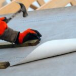 Synthetic roof underlayment being installed over the roof deck before shingles or metal roofing