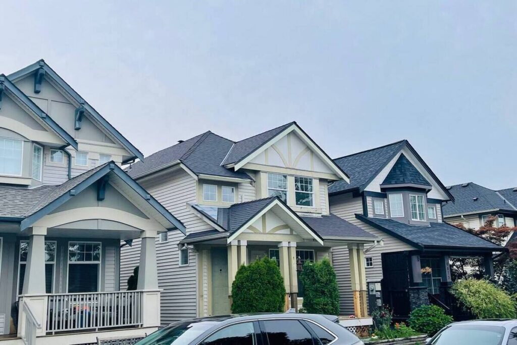 Multi-family residential homes with connected roof sections and dark asphalt shingles, showing strata roofing access and planning considerations.