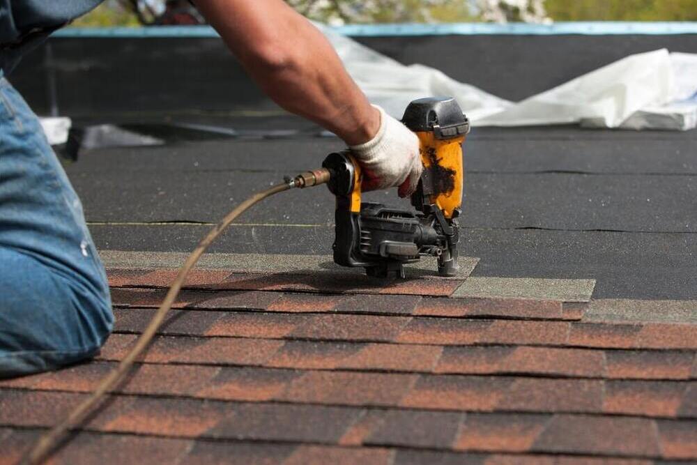 Roofer nailing asphalt shingles over new underlayment on a Vancouver home