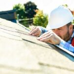 Contractor inspecting asphalt shingles on a residential roof