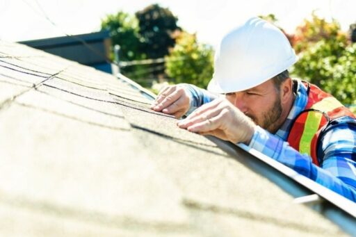 Contractor inspecting asphalt shingles on a residential roof